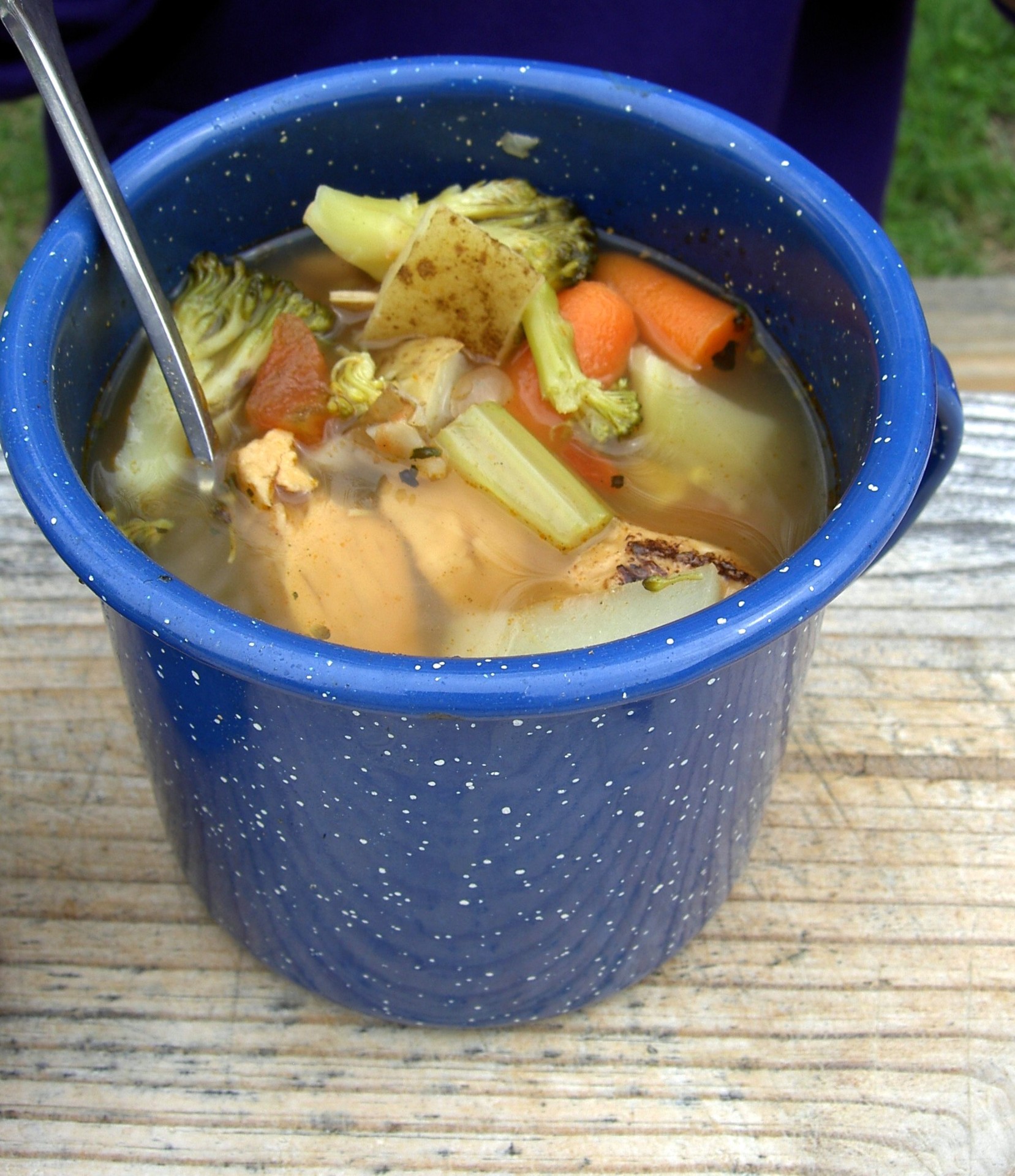 Bone broth with vegetables in a blue enamel mug